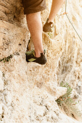 Unrecognizable man climbing a mountain. rock climbing shoes detail. risk sports and adventure. mountain activities.