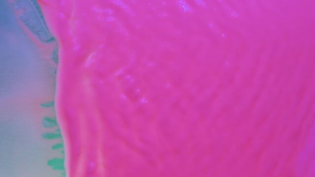 Slow motion. Wind blows away the pink fluorescent paint from the green background. View from above