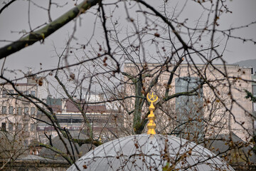 Roof and top of small masjid established by ottoman empire in bursa called as Koza han with star and crescent as golden yellow color in Bursa during rain and overcast weather covered by dried branches © SKahraman