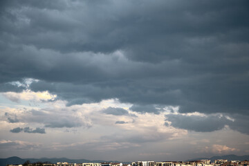Overcast sky and rain clouds with sunshine reflection on clouds over the city house and apartments 