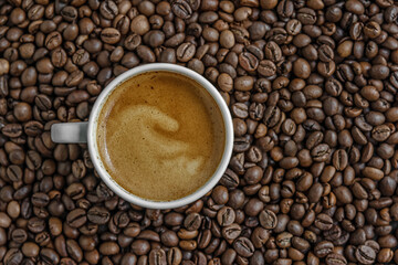 aromatic freshly brewed coffee in a white porcelain cup among coffee beans top view