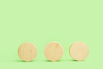 Tres circulos de madera sobre un fondo verde claro liso y aislado. Vista de frente. Copy space