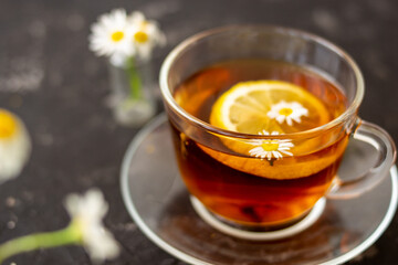 chamomile tea with lemon in a transparent cup on a black background. Breakfast concept, herbal tea.