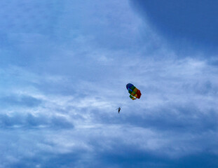 Naklejka na ściany i meble Two men are sailing on a colorful and bright parachute against the blue sky. Copy space