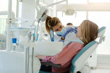 Perfect smile!Female dentist is examining her beautiful patient in dentist’s office.