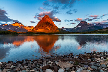dramatic summer sunrise in Swift Current Lake in Many Glacier area in Glacier National park  with...
