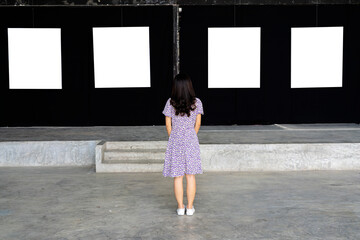A woman standing and looking at a blank picture frame