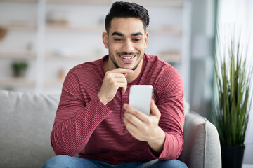 Positive arab guy using brand new mobile phone