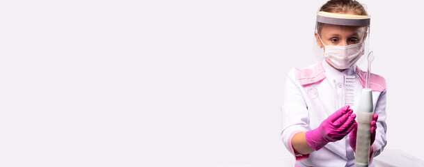 Banner, long format on light grey background. Healthy, beauty concept. A portrait of a female doctor wearing white gown, medical mask and face shield holding and showing cosmetic appliance.