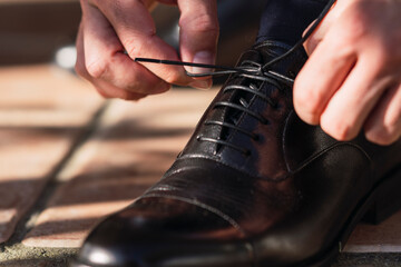 Detalle de un zapato lazando los cordones de un novio el día de su boda