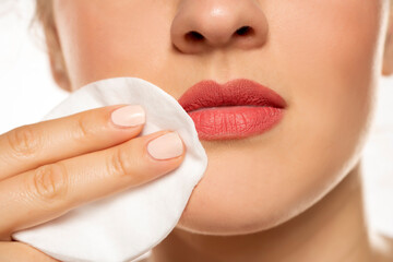 woman cleans makeup from her lips with a cotton pad