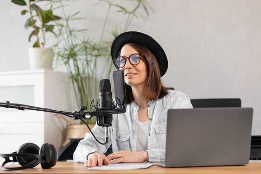 beautiful european woman podcaster with headphones and microphone records podcast in recording studio, audio content recording for radio show or commercial, female hiptester records podcast or voice