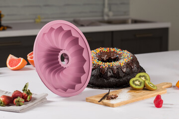 round purple silicone bunny mold for baking cakes, chocolate, next to fruits and greens mint, on a...