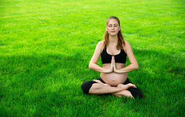 Pregnant woman sits in yoga posies and meditates.