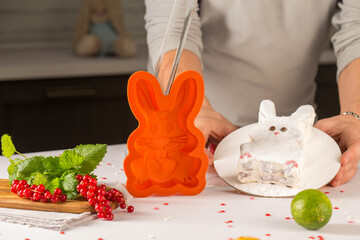 orange silicone mold rabbit for baking cakes, standing behind a man and hands, next to fruits and...