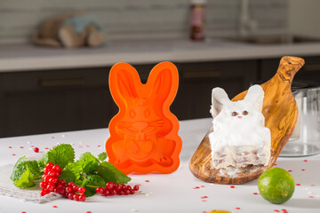 orange silicone mold rabbit for baking cakes, standing behind a man and hands, next to fruits and...