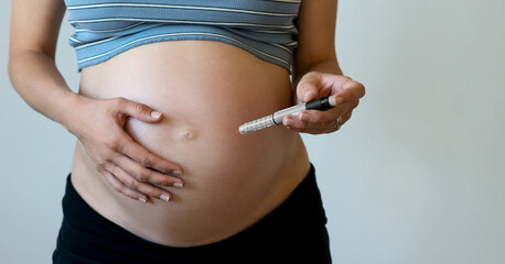 Pregnant woman makes injection of insulin in her belly.