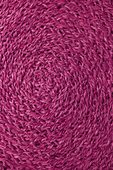 Spiral texture of magenta colored woven water hyacinth place mat