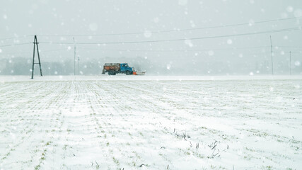 Snow blizzard in the winter field. Car in the field on a natural background. Snow plow clears the...
