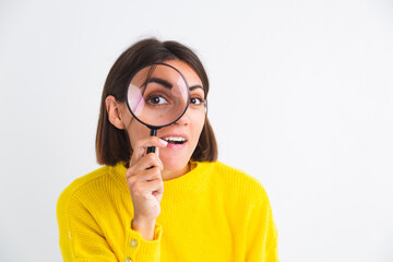 Pretty woman in yellow sweater on white background held magnifier happy positive playful