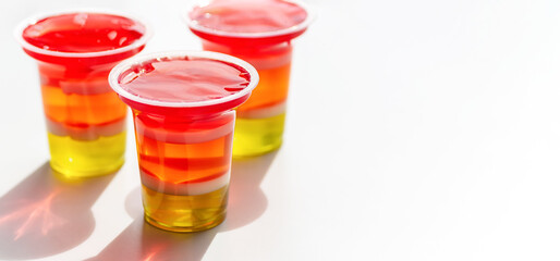 Colorful rainbow jelly on white background, fruit jelly dessert for party. Close-up. Copy space.
