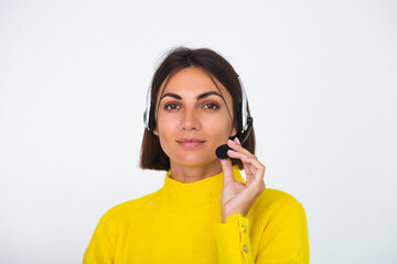 Pretty woman in yellow sweater on white background manager with headphones happy positive welcoming smile