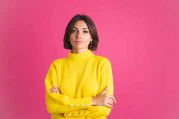 Fototapeta premium Beautiful woman in bright yellow sweater isolated on pink background look to camera with confident smile