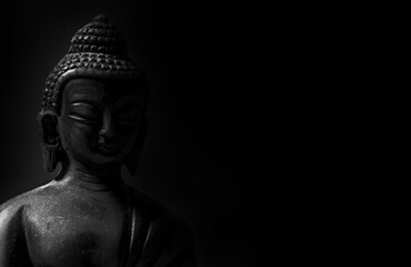 black and white picture of buddha statue isolated on black background with copy space - head close up
