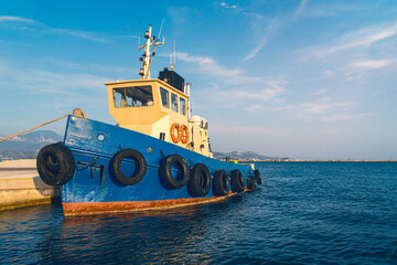 old tugboat moored in the harbor with a beautiful mediterranean sea landscape