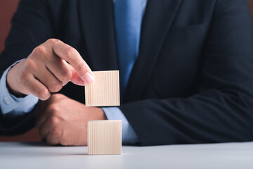 Hand of businessman arranging empty wooden blocks. Close-up photo. Space for text. Business and strategy planning concept