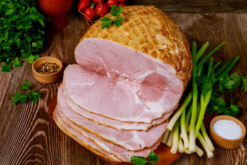 Delicious cooked ham on a wooden board with green onion and radish.