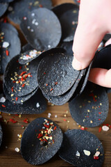 Fototapeta na wymiar Black chips with spices in hand. Black food.