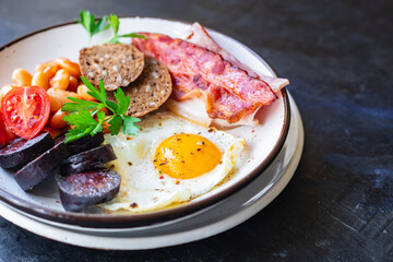 english breakfast fried egg fresh black pudding blood sausage, cereal bread, beans, bacon, scrambled eggs healthy meal snack copy space food background rustic 