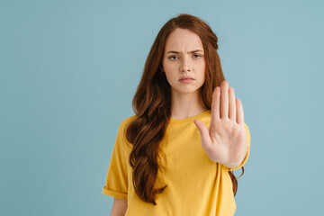 Young ginger white woman showing stop gesture and looking at camera - obrazy, fototapety, plakaty