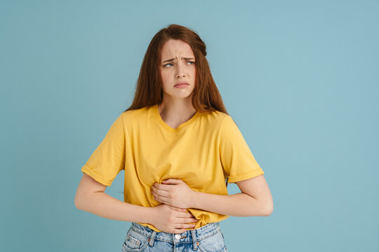 Young ginger white woman with stomachache looking aside