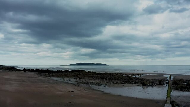 Aerial low view of drone rising over  beach landscape and revealing the Irish sea and Lambay Island on a cloudy evening  Donabate beach in summer, Dublin, Ireland