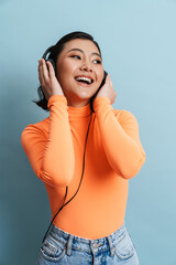 Young asian woman smiling while listening music with headphones