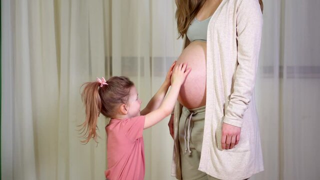 child stroke belly of pregnant mother. Pregnant woman and her todler daughter at home. concept of pregnancy, fatherhood. Young woman during her second pregnancy. Motherhood, family, parenting concept.