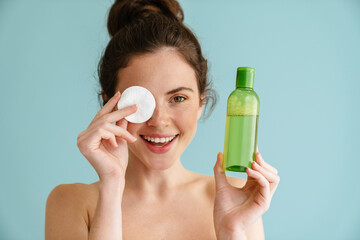Half-naked brunette woman posing with cotton pad and facial lotion © Drobot Dean