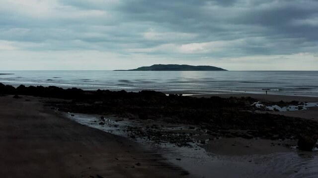 Low aerial view over beach landscape and revealing the Irish sea and Lambay Island on a cloudy evening  Donabate beach in summer, Dublin, Ireland