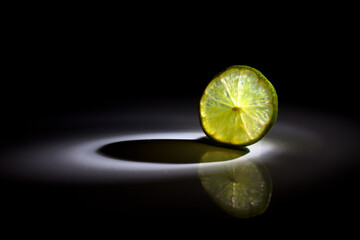 A slice of lemon fruit slice isolated on black background with a beautiful back light