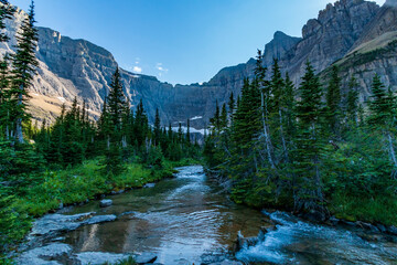 partially snow covered jagged mountain peaks of Glacier National park near Iceberg Lake trail during summer.