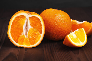 Oranges on a wooden background. New Year concept. New Year's spirit. Christmas spirit. Half an orange. Orange slice near a whole orange