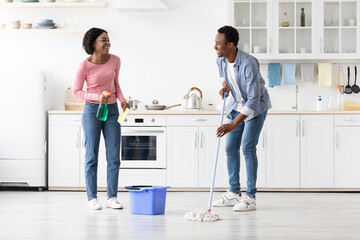 Beautiful black man and woman house-keepers cleaning kitchen