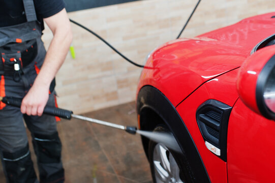 Man Worker Washing Red Car In Detailing Garage.