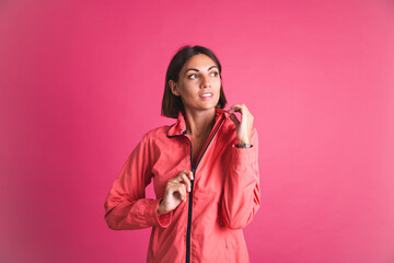 Young fit woman in sport wear jacket on pink background