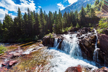 cascading stream under the summer blue sky in Glacier National Park in Montana.