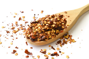 Dried red chilli flakes on the wooden spoon on white background.  