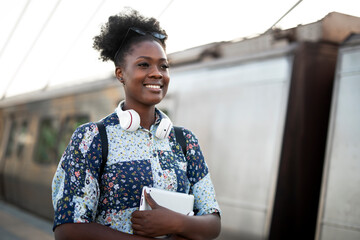 Happy young woman waiting for the train. African woman waiting for a subway train..