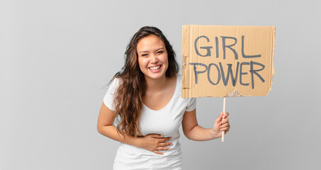 young pretty woman laughing out loud at some hilarious joke and holding a girl power banner